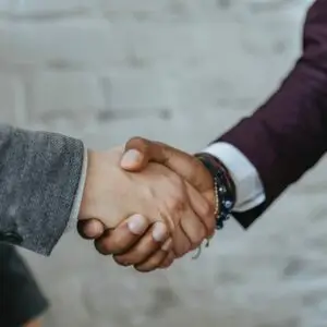 Zwei Geschäftsleute bei einem professionellen Handschlag, symbolisch für die vertrauensvolle Zusammenarbeit und individuelle Unterstützung durch erfahrene Jobcoaches bei PROFESCO