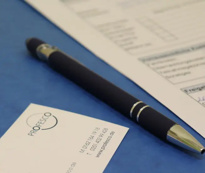 Stilvoller Stift auf einem blauen Dokument, symbolisiert die Professionalität und Detailgenauigkeit unserer Coaching-Services.