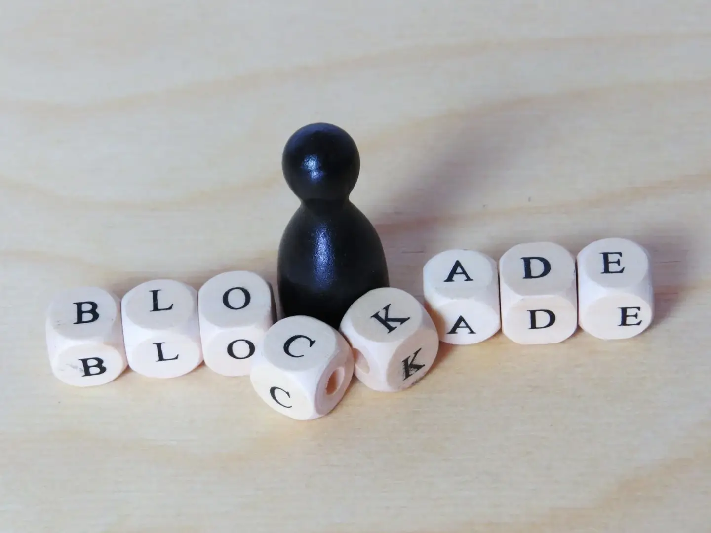 Schachfigur neben Würfeln mit dem Wort 'BLOCKADE', symbolisiert das Überwinden von Hindernissen im AVGS-Coaching.